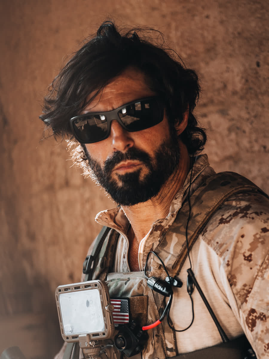 Portrait of an operator in desert camouflage with the cased phone on his kit